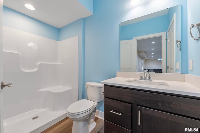 bathroom featuring vanity, toilet, wood-type flooring, and a shower