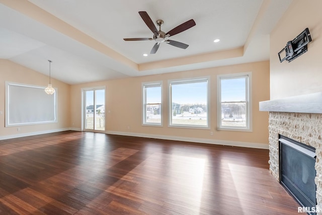 unfurnished living room with a tray ceiling, ceiling fan, a fireplace, and dark hardwood / wood-style floors