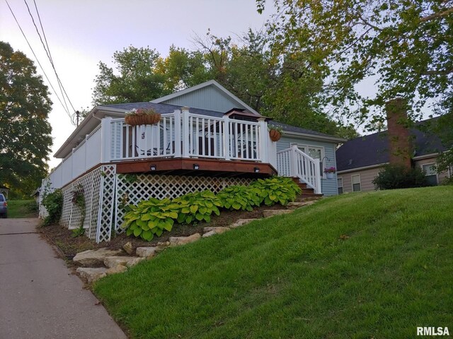 rear view of property featuring a lawn and a wooden deck