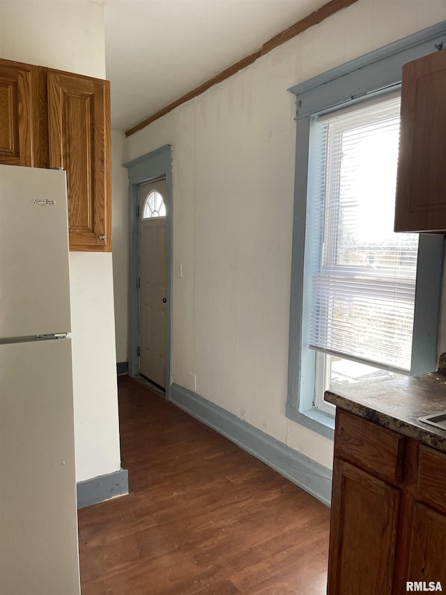 kitchen featuring dark hardwood / wood-style floors, white refrigerator, and crown molding