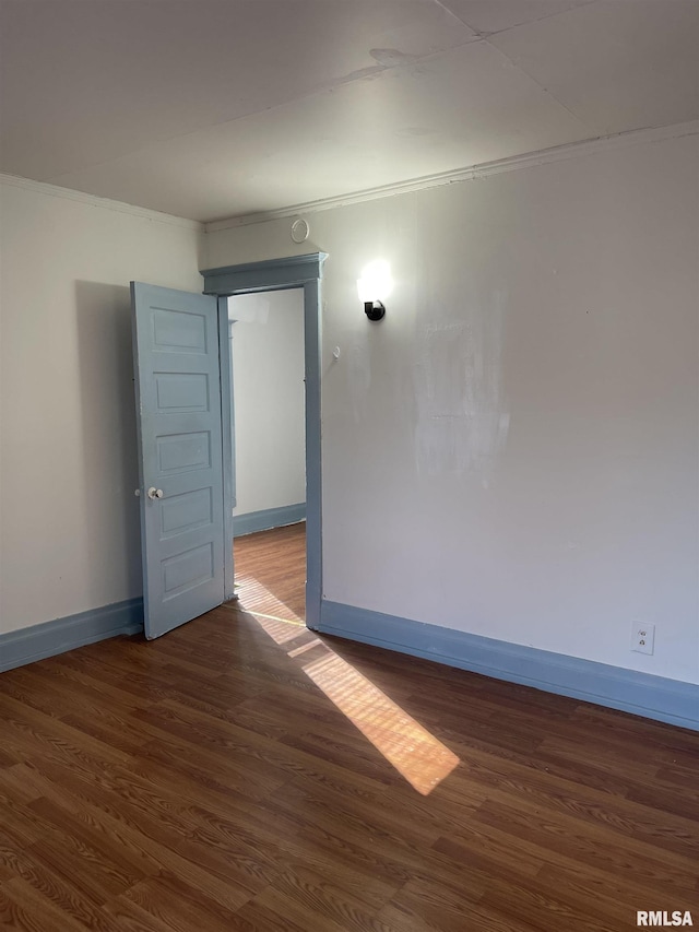 empty room with crown molding and dark hardwood / wood-style floors