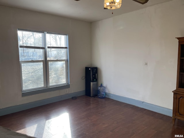 empty room featuring ceiling fan, plenty of natural light, and dark hardwood / wood-style floors