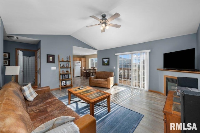 living room with ceiling fan, lofted ceiling, and light hardwood / wood-style flooring