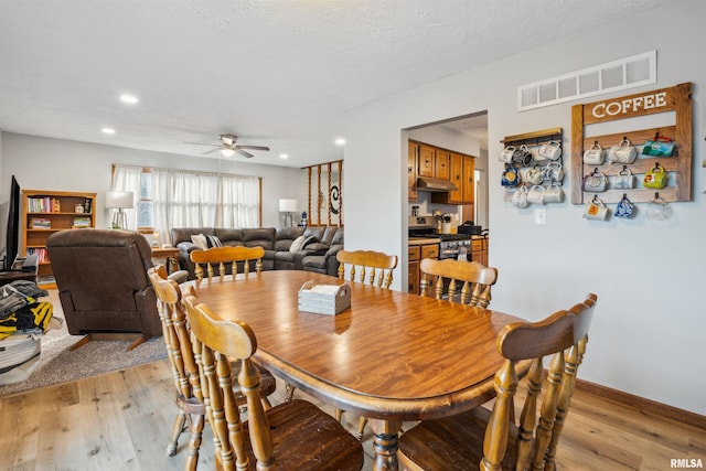 dining room featuring a textured ceiling, ceiling fan, and light hardwood / wood-style floors