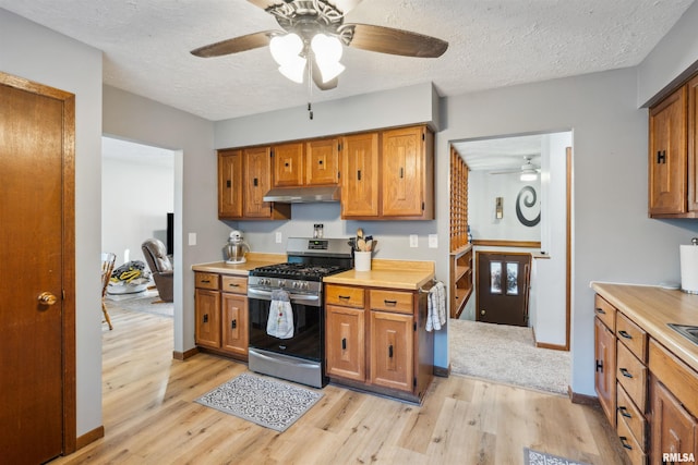 kitchen with stainless steel gas range oven, ceiling fan, a textured ceiling, and light hardwood / wood-style flooring