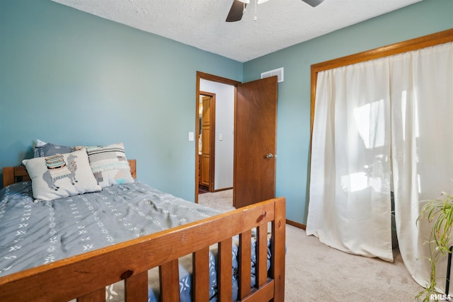 carpeted bedroom featuring ceiling fan and a textured ceiling