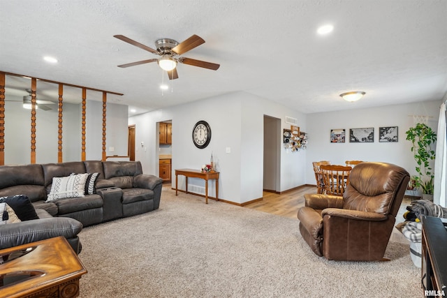 living room featuring light colored carpet, ceiling fan, and a textured ceiling