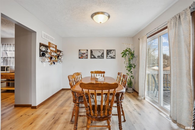 dining space featuring light hardwood / wood-style floors and a textured ceiling