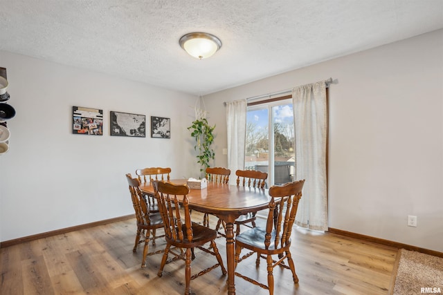 dining space featuring a textured ceiling and light hardwood / wood-style flooring