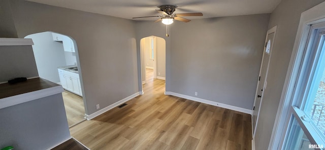 empty room with ceiling fan and light hardwood / wood-style flooring