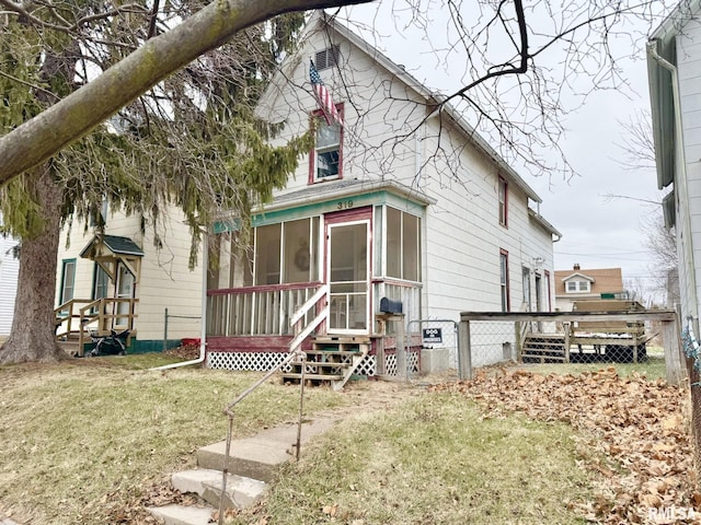 rear view of house featuring a lawn and a sunroom