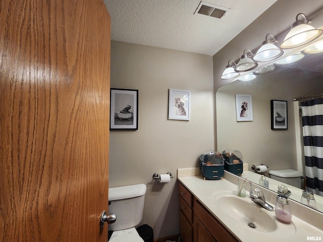 bathroom featuring vanity, toilet, a textured ceiling, and walk in shower