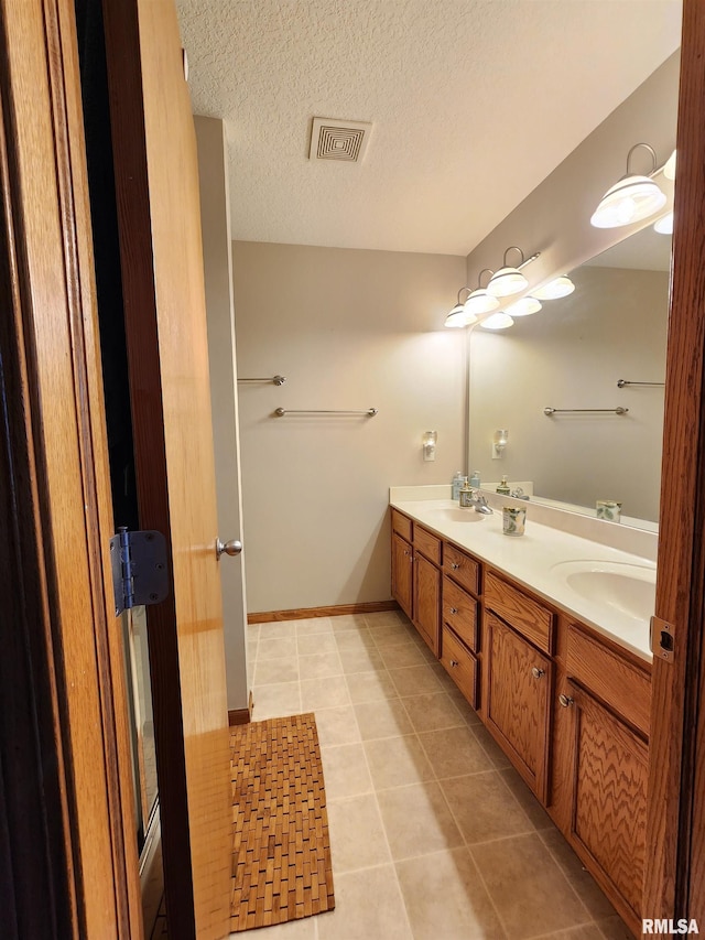 bathroom featuring tile patterned flooring, vanity, and a textured ceiling