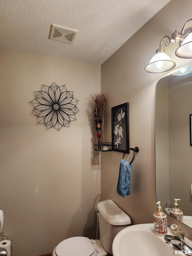 bathroom with a textured ceiling, toilet, and sink