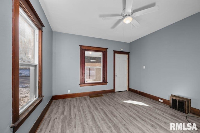 empty room with ceiling fan, plenty of natural light, and light wood-type flooring