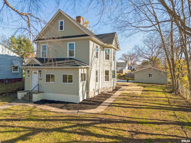 rear view of house featuring a lawn, entry steps, and a chimney