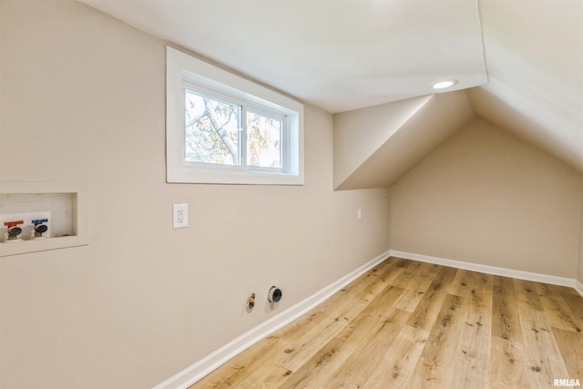 additional living space featuring vaulted ceiling and light wood-type flooring