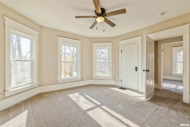 carpeted empty room with ceiling fan and a healthy amount of sunlight