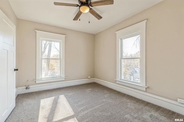 carpeted spare room featuring a wealth of natural light and ceiling fan