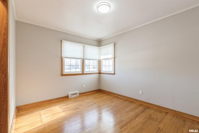 empty room with crown molding and light wood-type flooring