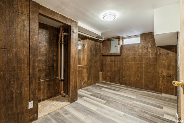 basement with wood walls and light wood-type flooring