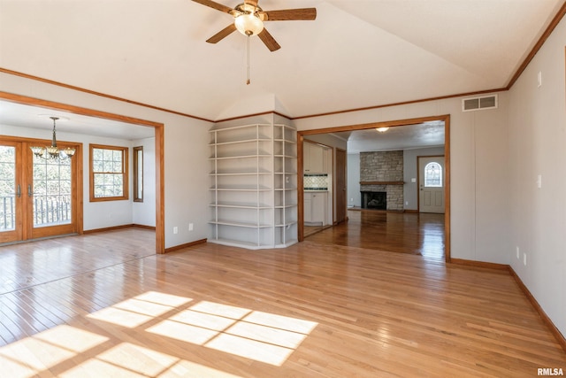 unfurnished living room featuring wood-type flooring, ceiling fan with notable chandelier, a brick fireplace, and french doors