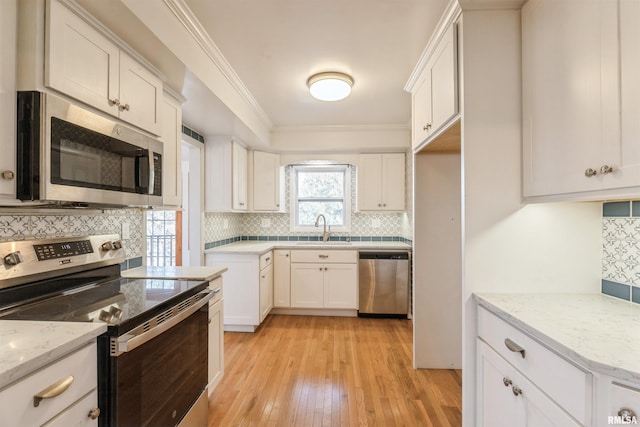 kitchen with backsplash, sink, light stone countertops, white cabinetry, and stainless steel appliances