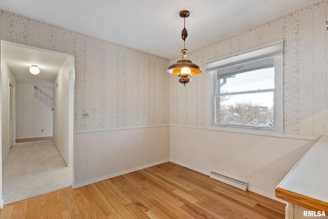 unfurnished room featuring baseboard heating and hardwood / wood-style floors