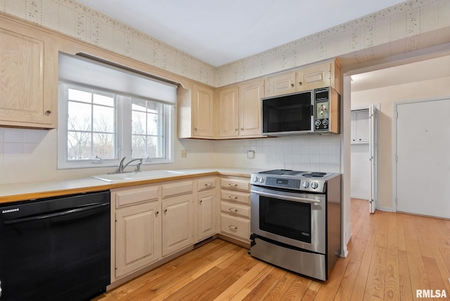 kitchen featuring sink, black appliances, and light hardwood / wood-style flooring