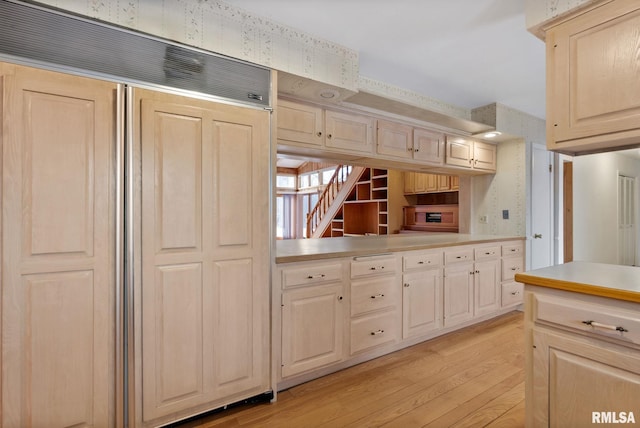 kitchen with paneled built in refrigerator and light hardwood / wood-style floors