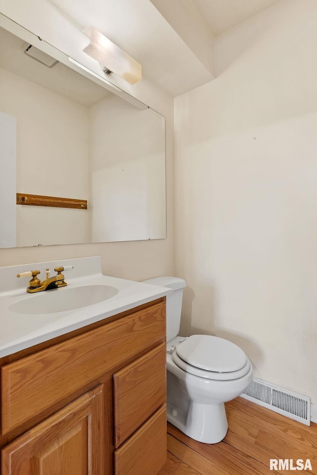 bathroom with toilet, hardwood / wood-style flooring, and vanity