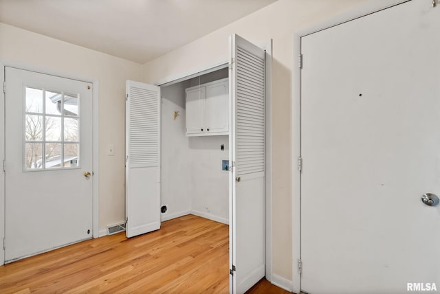 laundry area featuring cabinets and light hardwood / wood-style floors