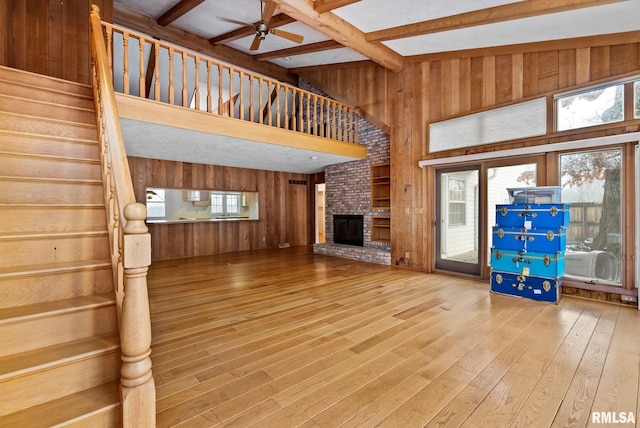 unfurnished living room with a fireplace, plenty of natural light, and beamed ceiling