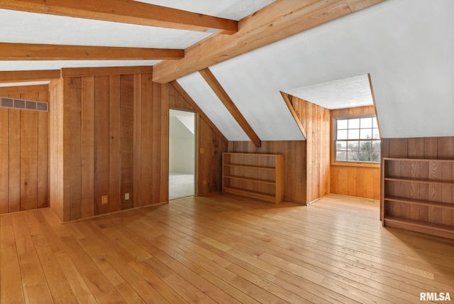 additional living space featuring vaulted ceiling, light wood-type flooring, and wooden walls