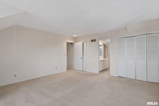 unfurnished bedroom featuring ensuite bathroom and light colored carpet