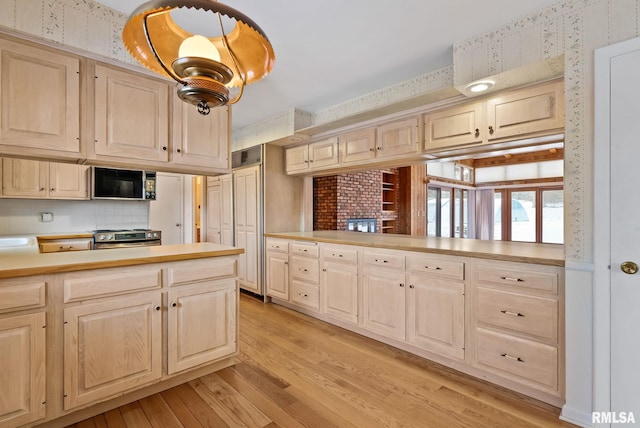 kitchen featuring stainless steel range, kitchen peninsula, decorative backsplash, and light hardwood / wood-style floors