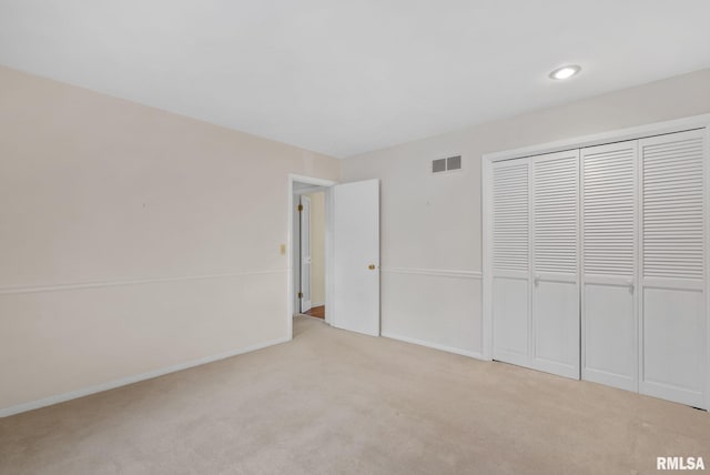 unfurnished bedroom with light carpet and a closet