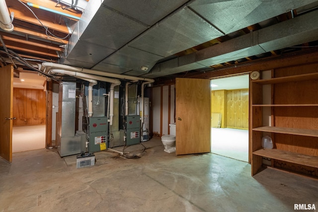 basement with heating unit, wooden walls, and gas water heater