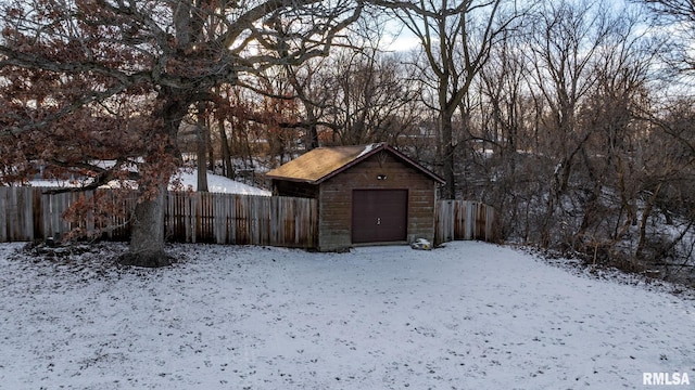 yard layered in snow with an outdoor structure and a garage