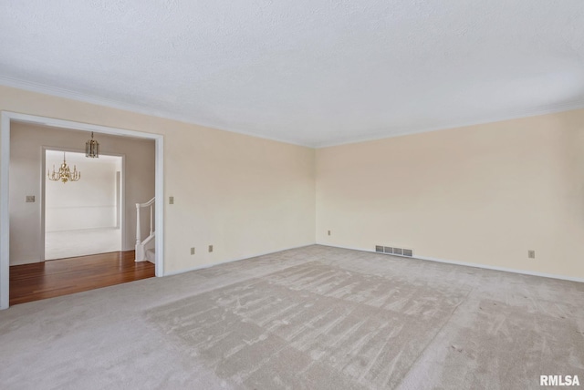 unfurnished room featuring a textured ceiling, light carpet, and a chandelier