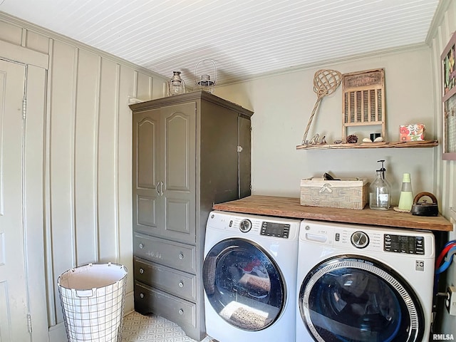 laundry area featuring cabinets, ornamental molding, and washing machine and clothes dryer