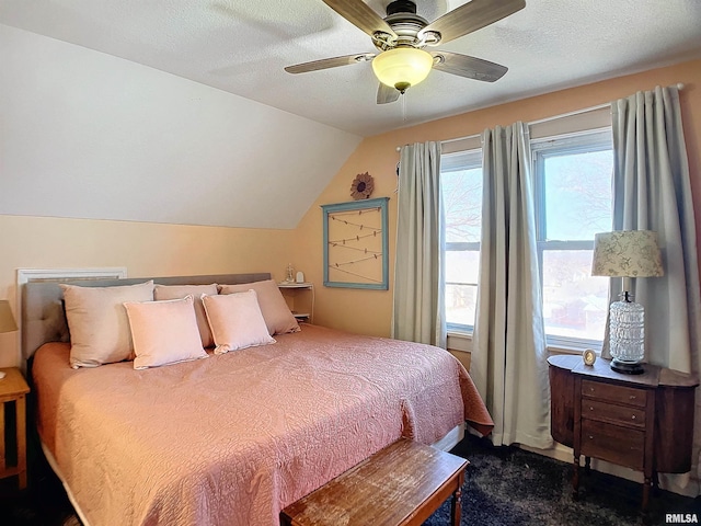 bedroom featuring dark carpet, vaulted ceiling, a textured ceiling, and ceiling fan