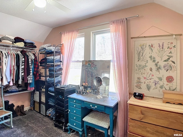 spacious closet featuring ceiling fan, vaulted ceiling, and dark colored carpet