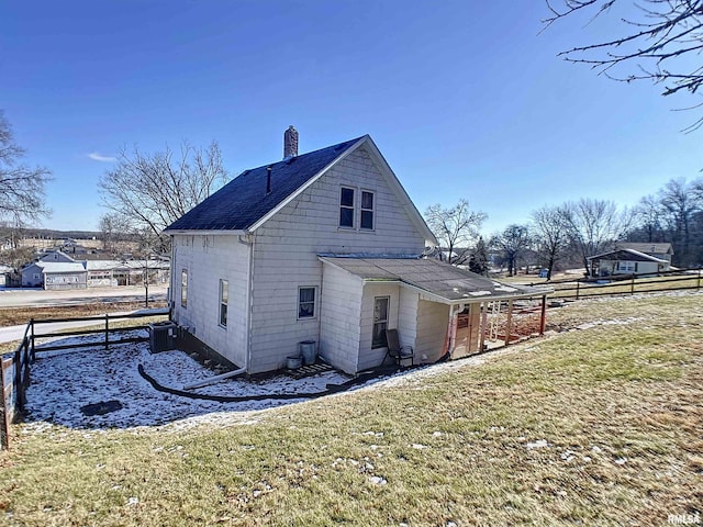 view of side of property with central AC unit and a lawn