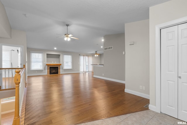 unfurnished living room featuring vaulted ceiling, ceiling fan, and light tile patterned flooring