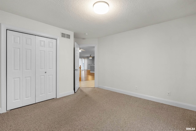 unfurnished bedroom with carpet floors, a textured ceiling, and a closet