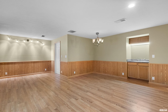 empty room featuring light hardwood / wood-style floors, an inviting chandelier, and sink