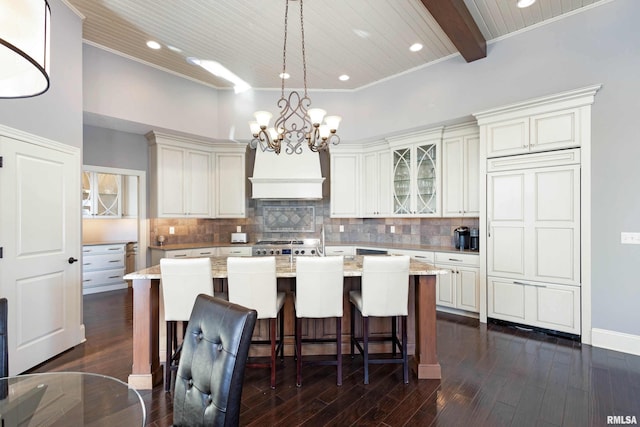 kitchen with beam ceiling, a kitchen island with sink, pendant lighting, and custom exhaust hood