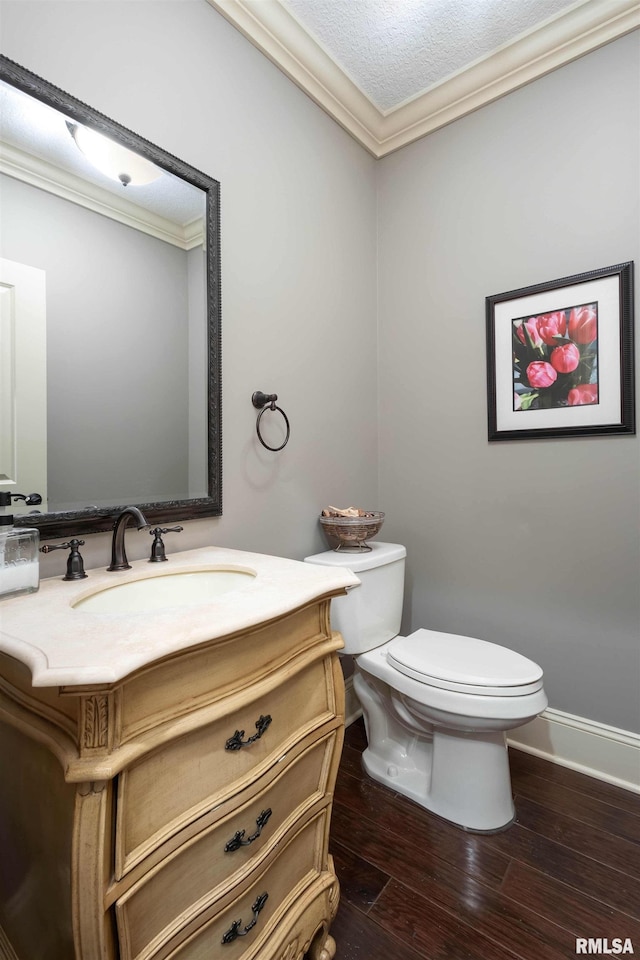 bathroom with a textured ceiling, vanity, crown molding, hardwood / wood-style flooring, and toilet