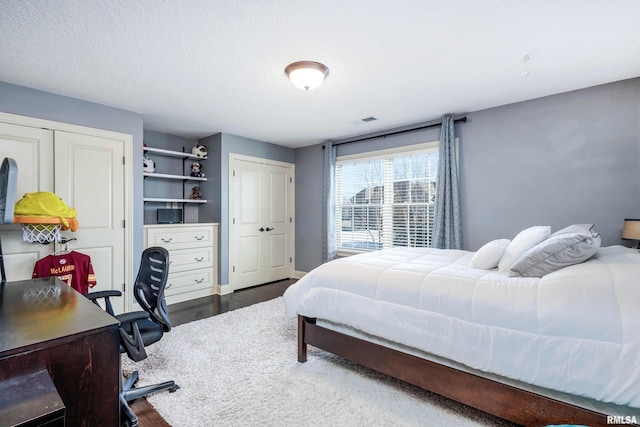 bedroom with multiple closets and dark wood-type flooring